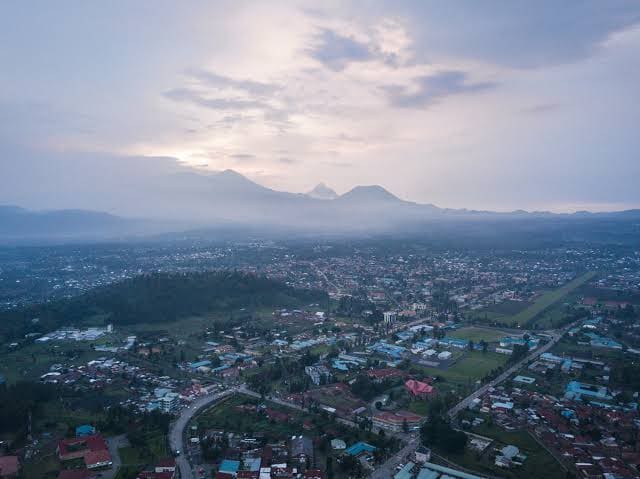 Aerial view of Musanze town at dusk with volcanoes in the background