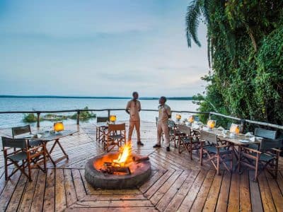 Couple on a lakeside lodge deck beside a fire pit