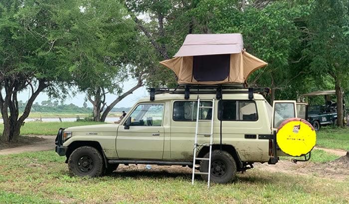 Land Cruiser with a rooftop tent set up for a camping safari in Rwanda