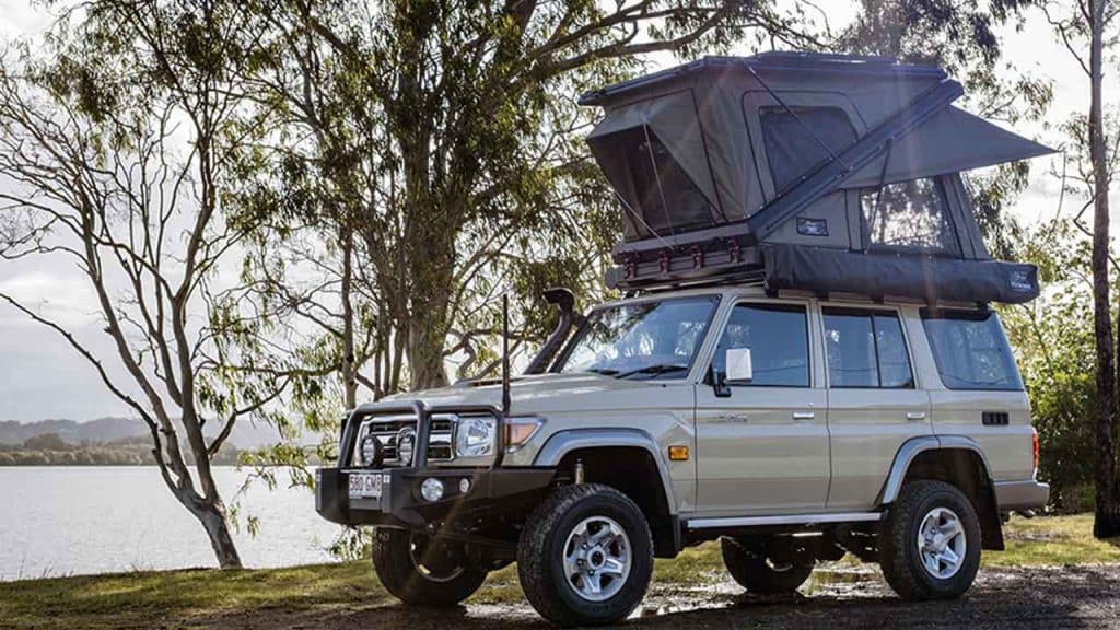 Land Cruiser with a rooftop tent beside a lake