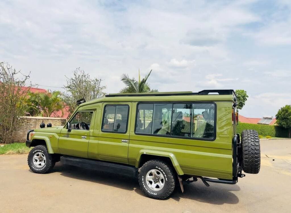 Olive safari Land Cruiser with pop-up roof parked on a Rwandan track