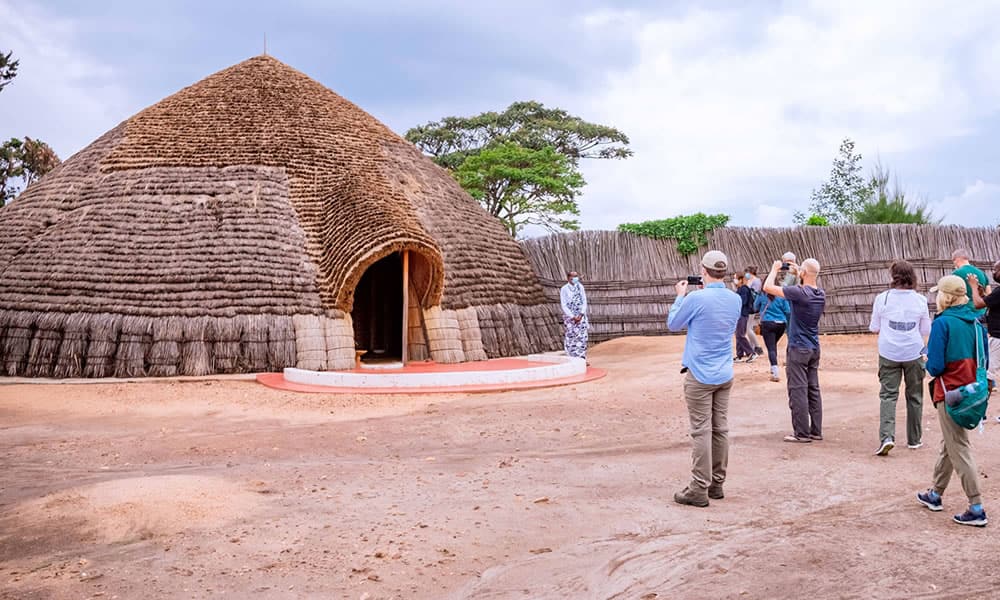 Visitors beside a reed hut at the King's Palace in Nyanza