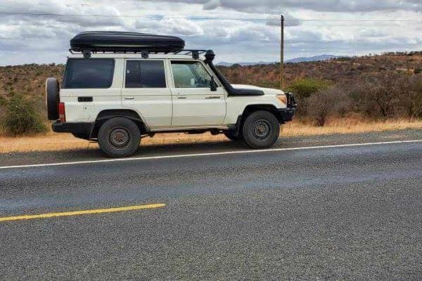 White Land Cruiser with roof rack on a tarmac road